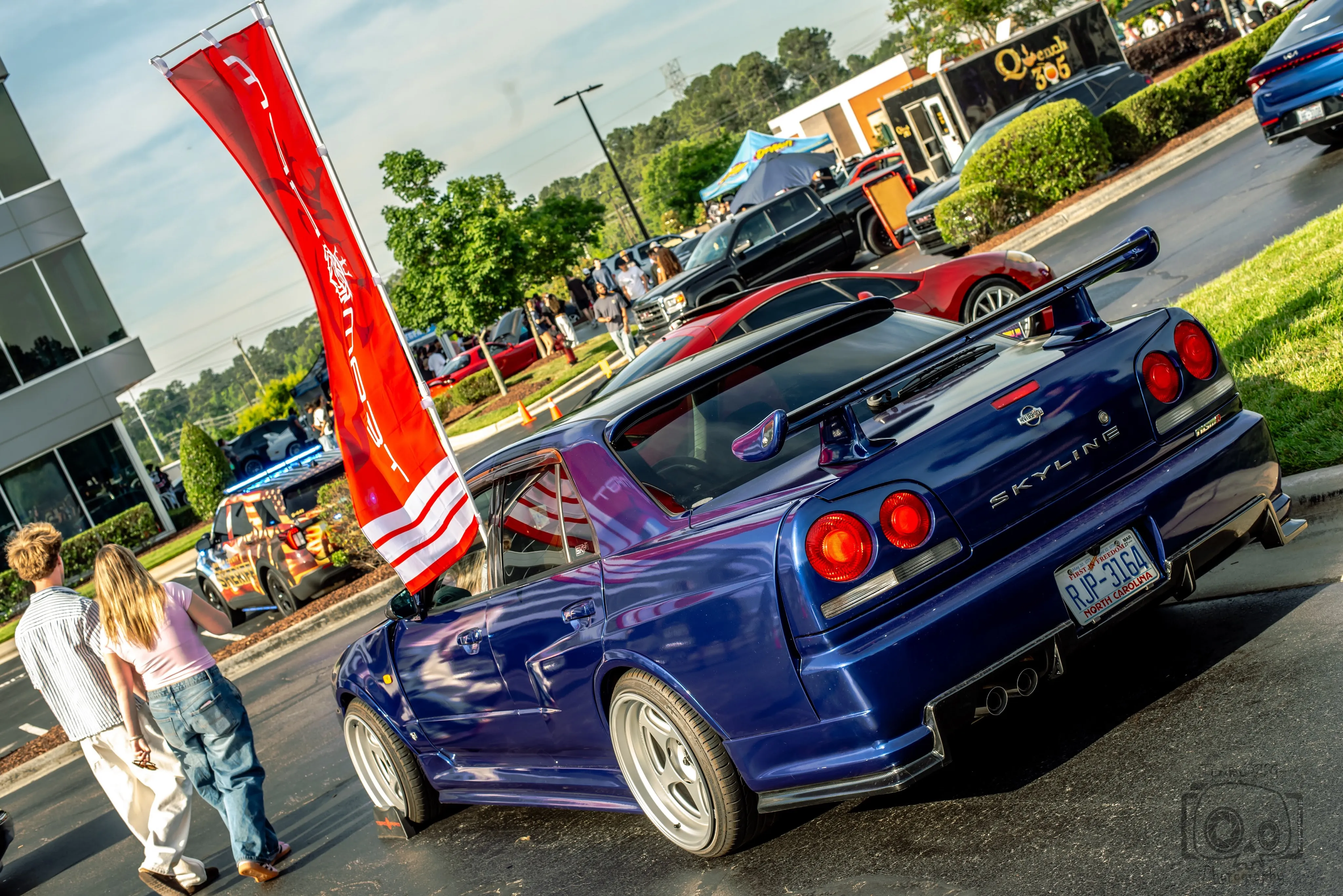 Blue Nissan Skyline R34 under the TEAM RPM flag at a meet